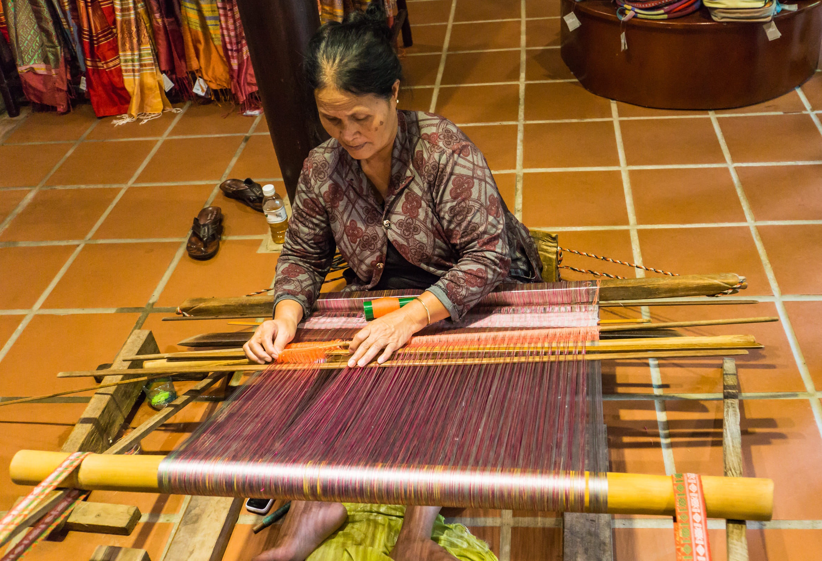 A Champa woman uses an antique wooden loom to weave silk at the Hội An Silk Village