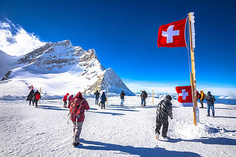 Tourists in front of Swiss flag on Jungfraujoch peak