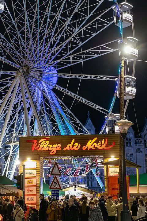 Crowds at the Christmas market chalets and ferris wheel in the Village de Noël