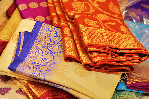 Closeup view of Banares silk saris in a textile shop, displayed in front of customers.