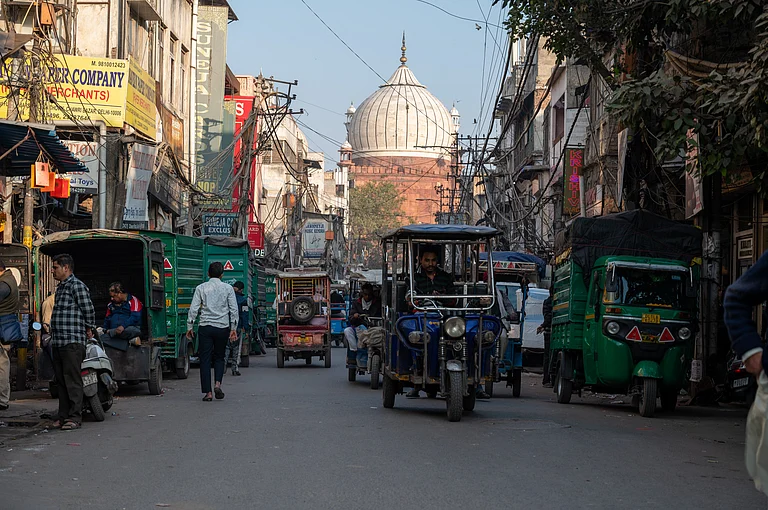 A street view of Old Delhi with the bulbous dome of Jama Masjid in the far end - Shutterstock