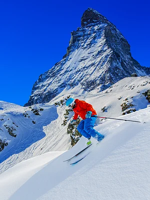 Shutterstock : Man skiing in deep fresh powder snow with Matterhorn in background in Swiss Alps