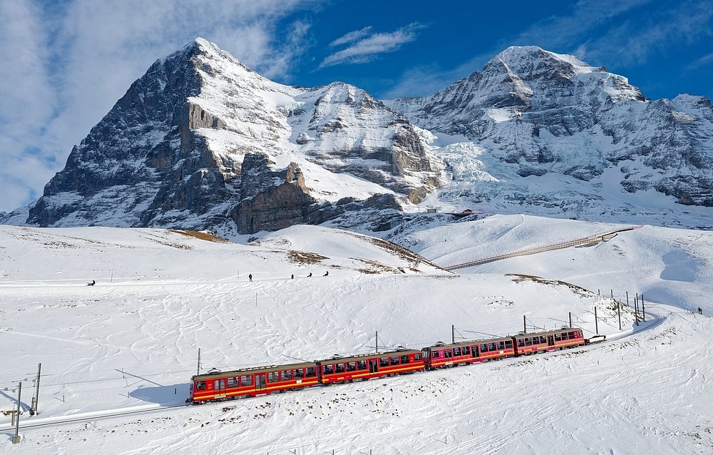 A cogwheel train travels on the railway from Jungfraujoch to Kleine Scheidegg on the snowy hillside in Bernese Highlands, Switzerland