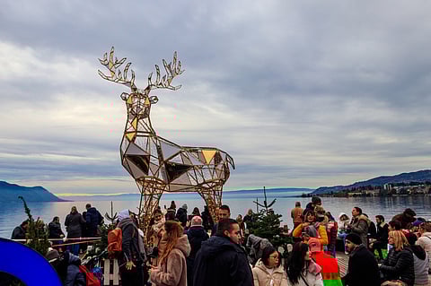 People take photo near a Christmas reindeer statue in Montreux, Switzerland