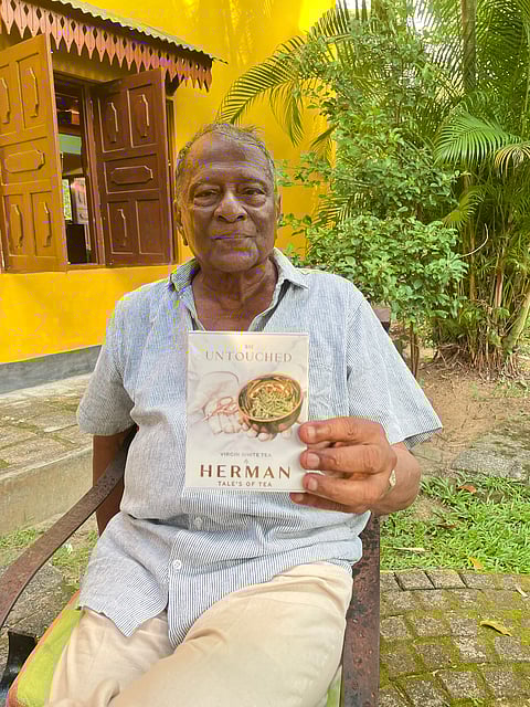Malinga Herman Gunaratne, the owner of the Handunugoda Tea Estate, holds up one of his books