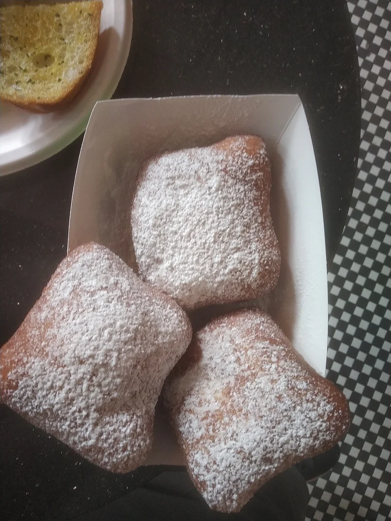 Beignets are a square bun made of dense flour, deep-fried and topped with demerara sugar