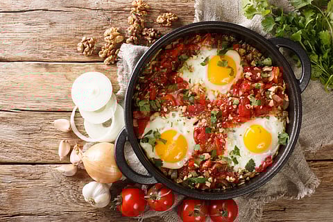 Chirbuli of fried eggs with tomatoes, onions and walnuts close-up 