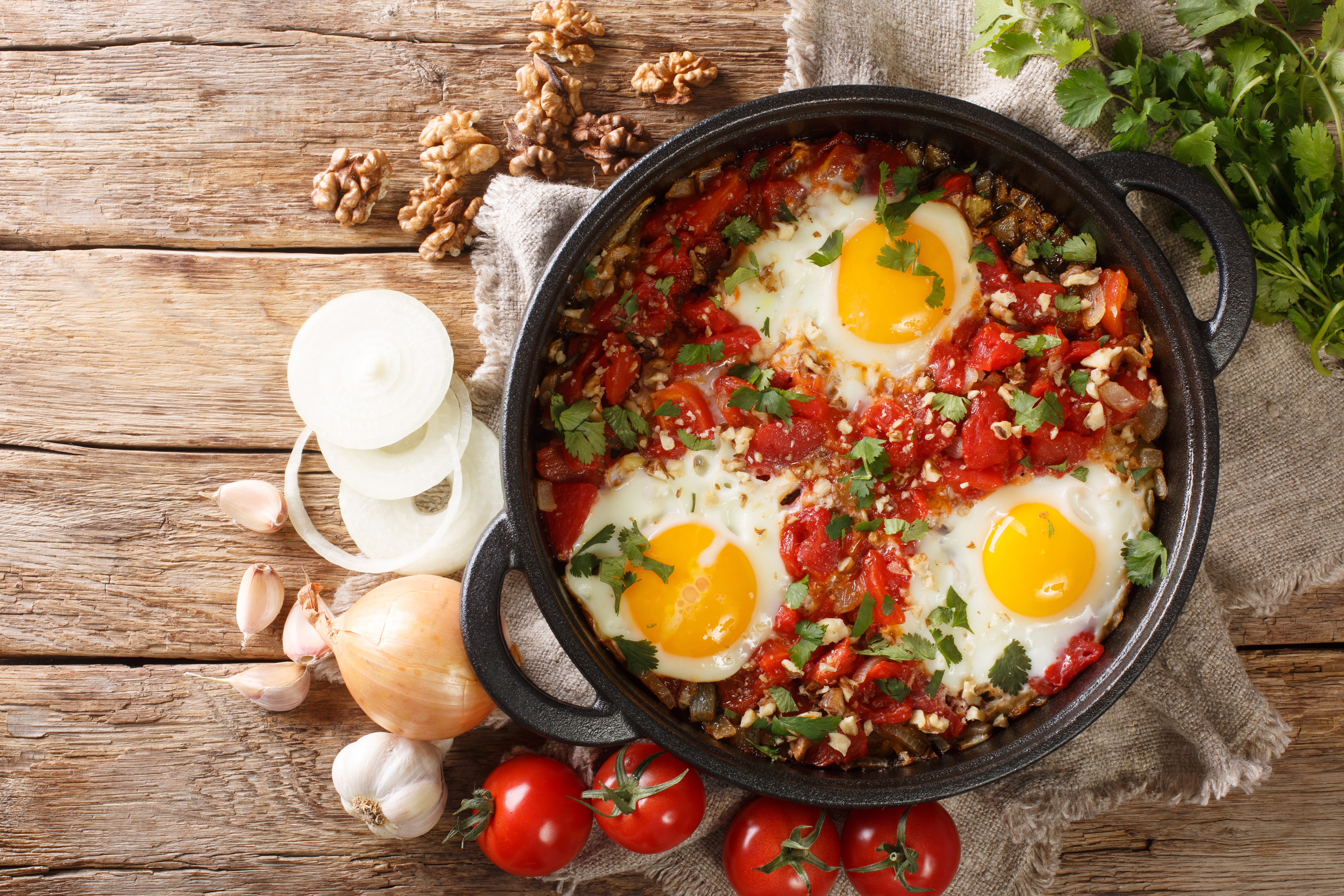 Chirbuli of fried eggs with tomatoes, onions and walnuts close-up