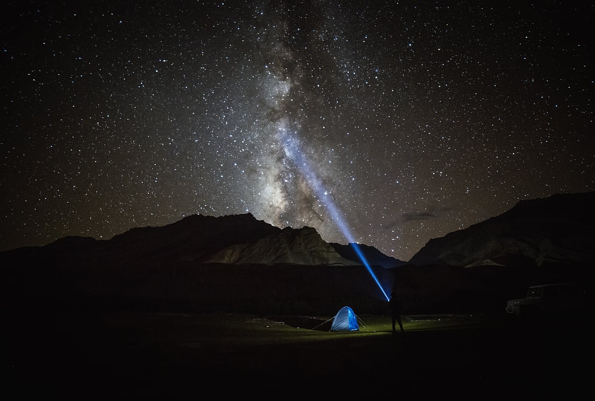 Milky way star shining above illuminated tents at the Himalayan mountain pass