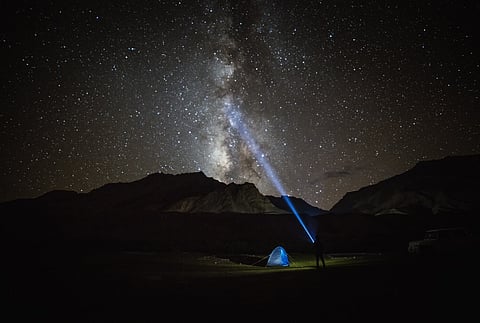 Milky way star shining above illuminated tents at the Himalayan mountain pass