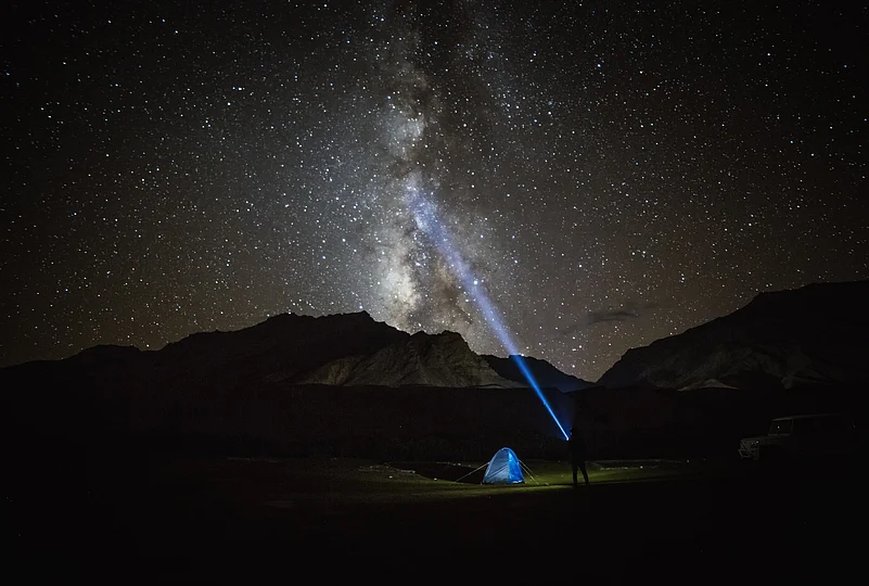Milky way star shining above illuminated tents at the Himalayan mountain pass