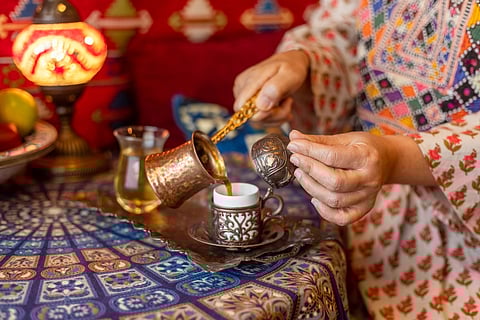 Pouring Turkish coffee from cezve into cup