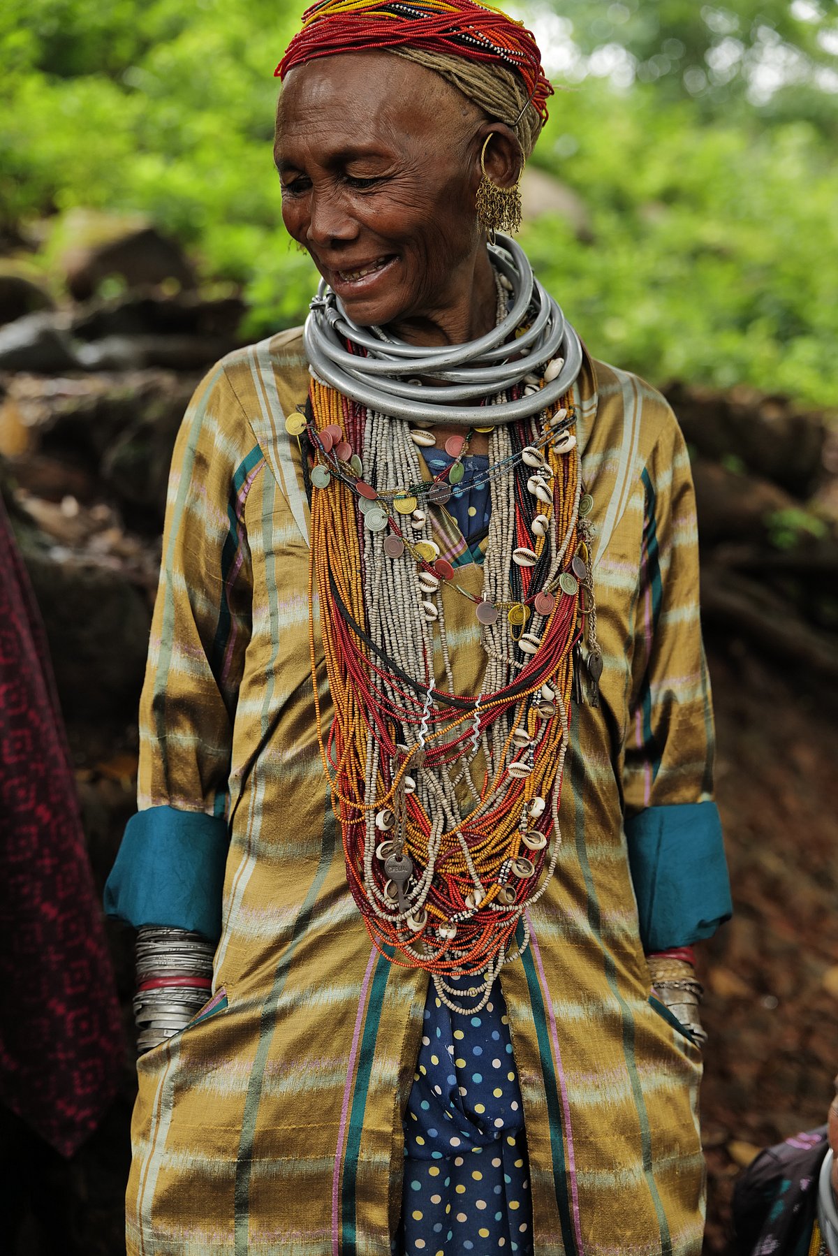 Bonda woman Sukri wears a chequered gold trench coat with Bonda accessories