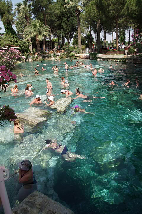 Tourists swim in the thermal pools amidst ancient Roman columns of the spa at Pamukkale Turkey