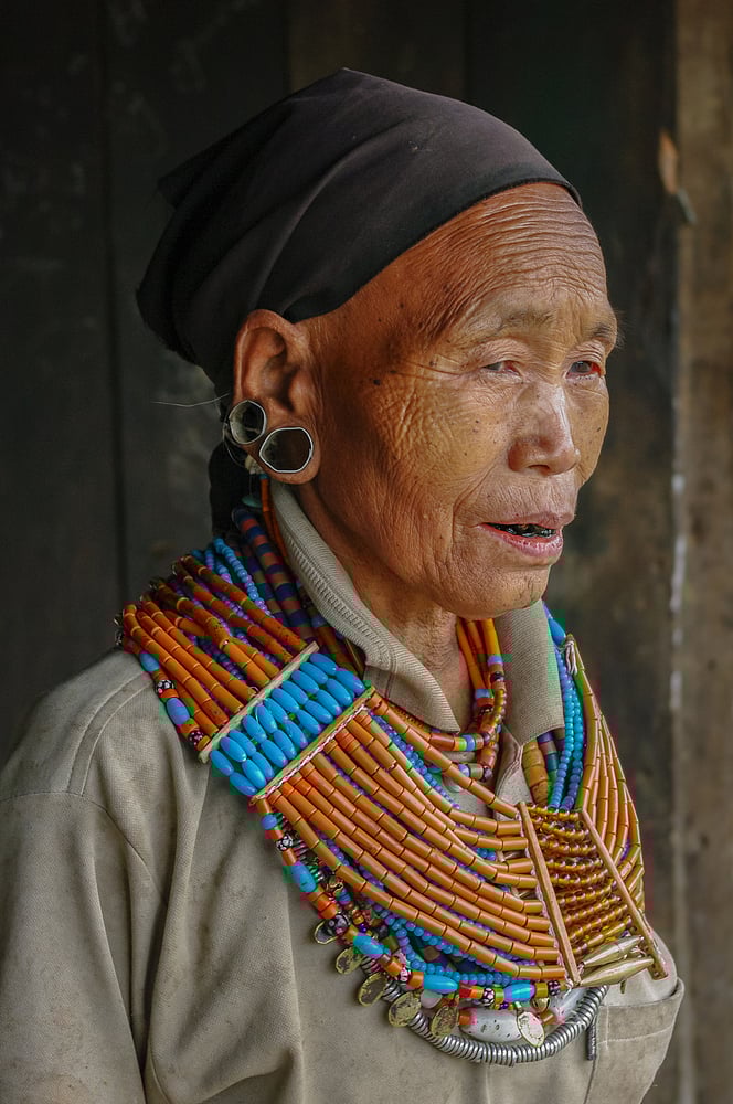 Portrait of old Naga Konyak tribe woman wearing traditional necklace and earrings