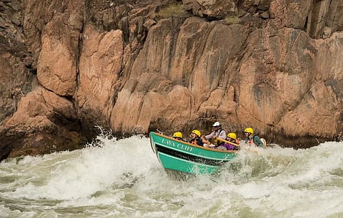 A guide rows a classic Grand Canyon dory through whitewater