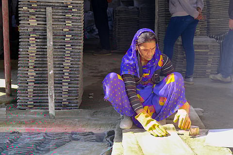 An employee of the TARA Nirman Kendra prepares a micro concrete roofing tile for drying