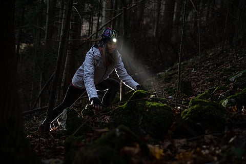 A woman hiking in the forest at night