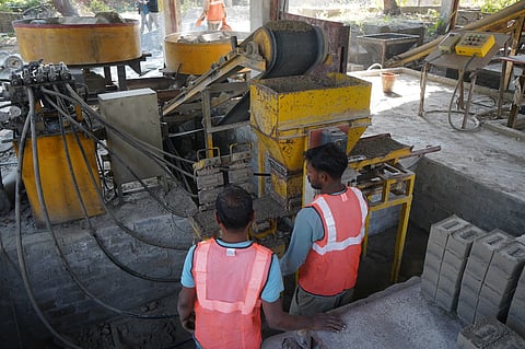 Employees of the TARA Nirman Kendra produce fly ash bricks