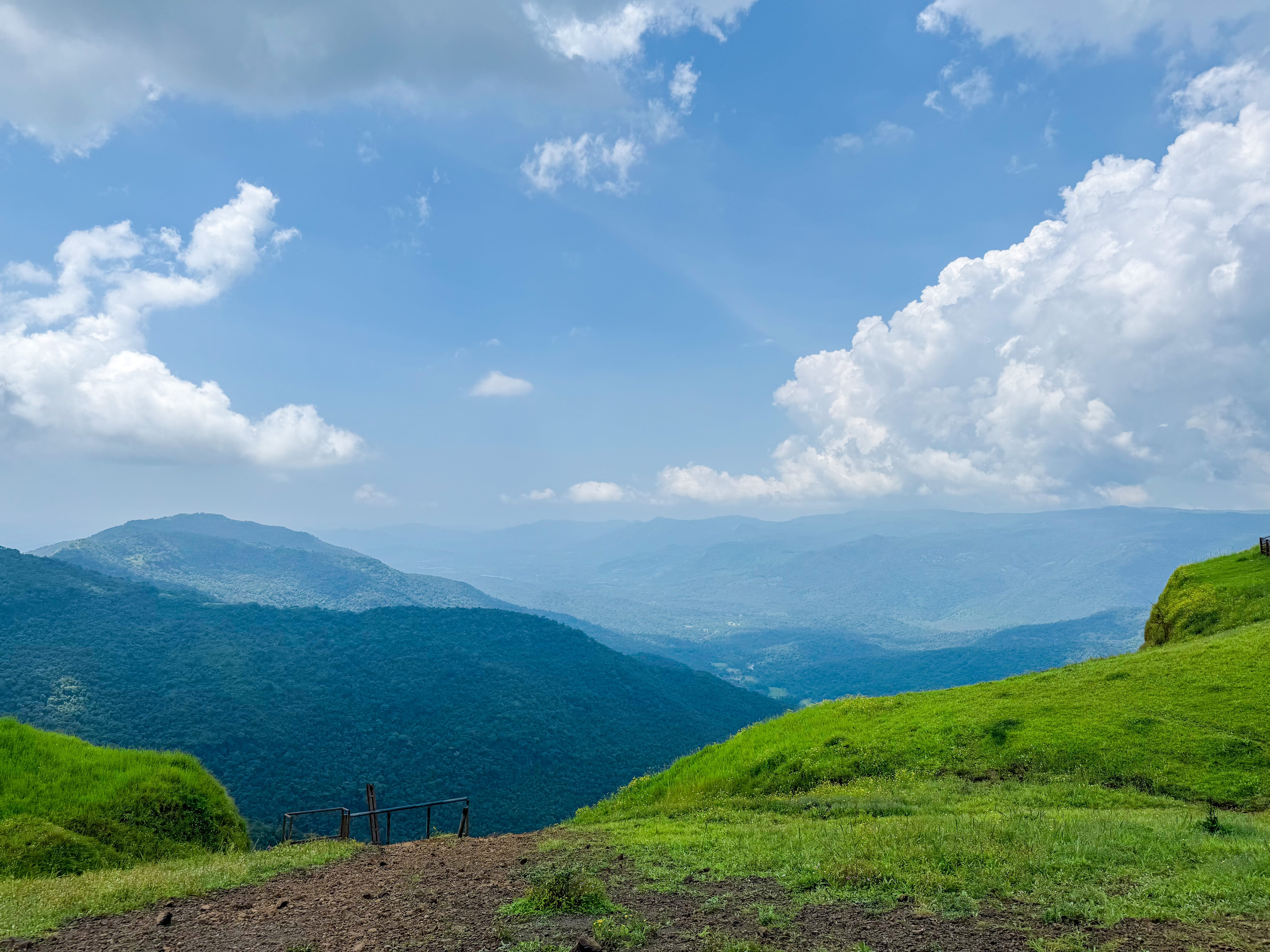 A landscape view from Tilari Nagar View Point, showcasing the lush green hills and expansive valleys of Belagavi