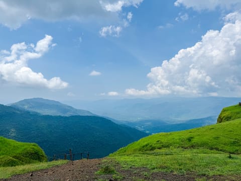 A landscape view from Tilari Nagar View Point, showcasing the lush green hills and expansive valleys of Belagavi