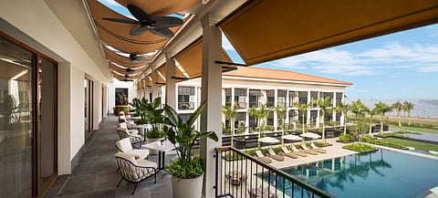 The balconies on either side of the azure pool have slatted wooden louvred shades