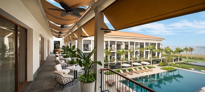 The balconies on either side of the azure pool have slatted wooden louvred shades