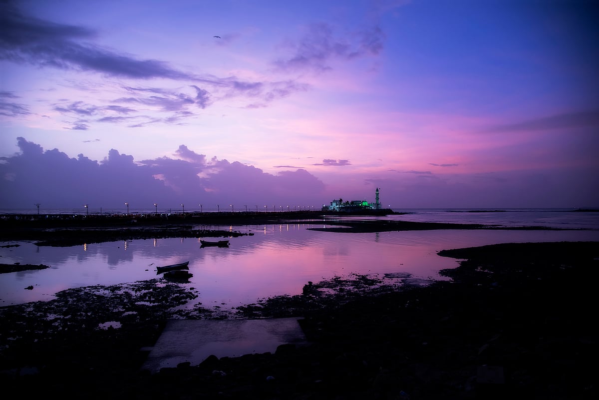 Mahyar Vaid/Shutterstock : The Haji Ali Dargah bathed in purple hues during sunset off the coast of Worli