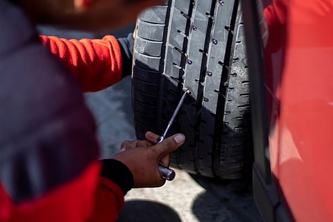 A person fixes a flat tyre using a tool from their tyre repair kit