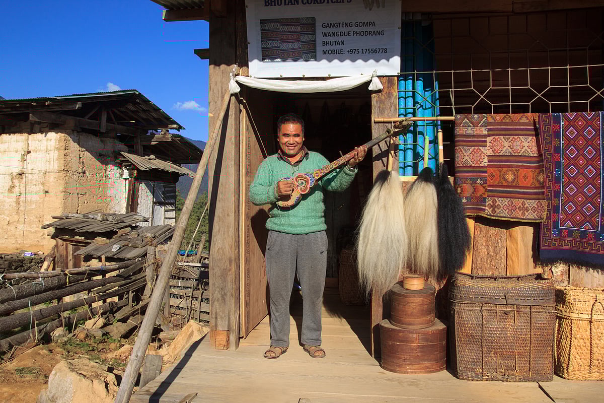 Wangdue stands outside his shop in the serene Gangtey Village. The quaint wooden shop is filled with traditional whisks made from the tail hair of a yak. His fingers glide effortlessly over the strings of the Dranyen, the most popular traditional musical instrument