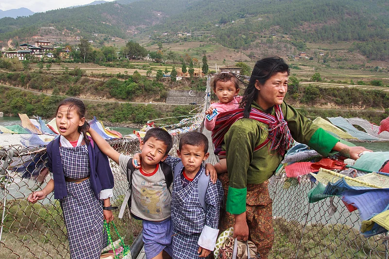 On a windy day near Punakha Dzong, a mother and her four children make their way across the famous hanging bridge that sways high above the Pho Chhu River below. This image captures a simple yet powerful moment of daily life in Bhutan, where family, nature and spirituality are deeply intertwined