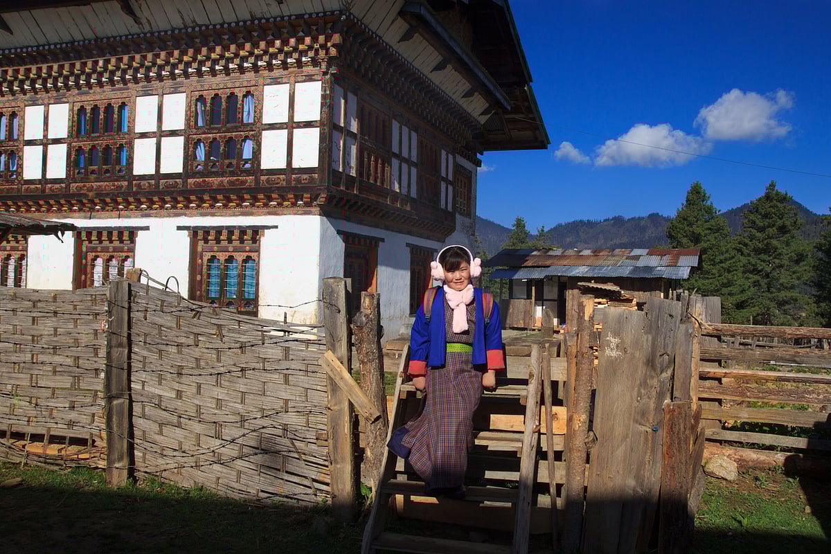 A young Bhutanese girl steps down outside her home, as she heads to school on a chilly morning. Wrapped in warm winter clothes, her ears are covered to shield her from the cold