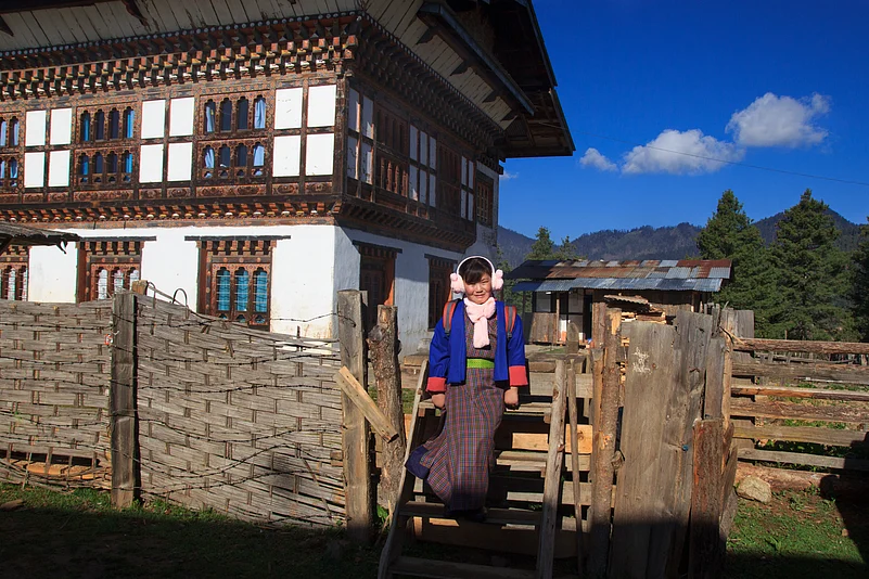 A young Bhutanese girl steps down outside her home, as she heads to school on a chilly morning. Wrapped in warm winter clothes, her ears are covered to shield her from the cold