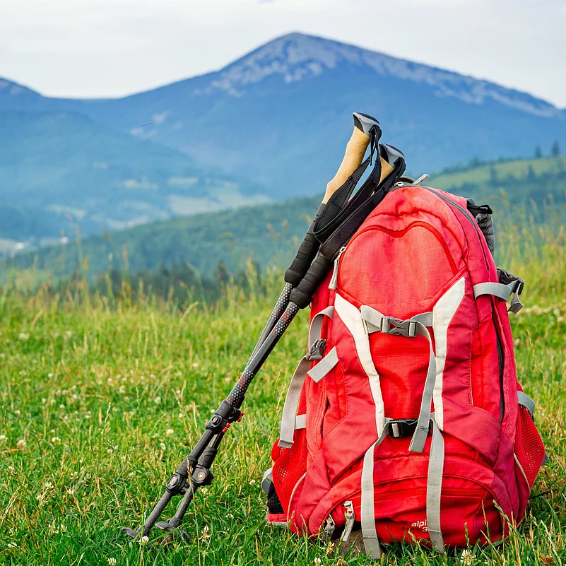 Trekking with a backpack and trekking poles along the ridge in the mountains.
