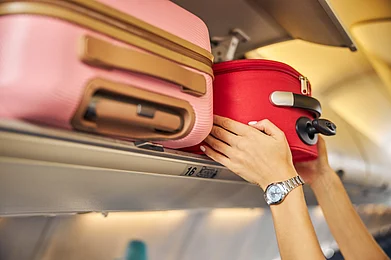 Shutterstock : A passenger places cabin baggage in the overhead compartment of an aeroplane