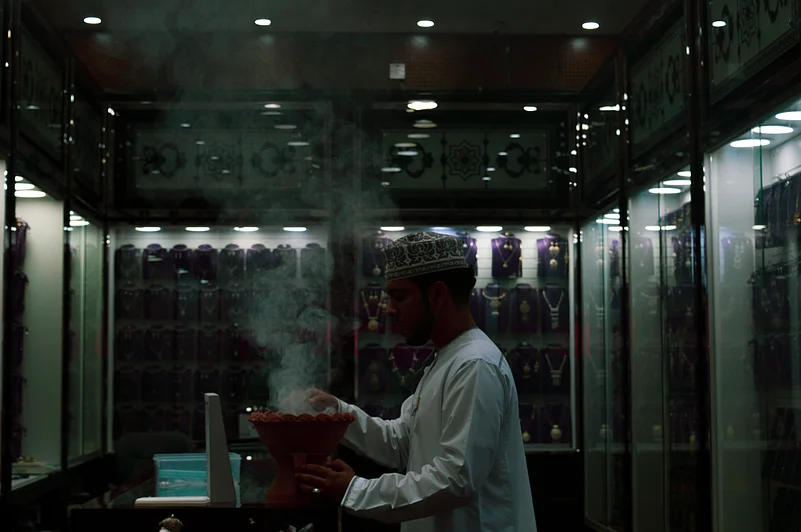 A show owner burns incense during sunset at the souq outside Nizwa Fort