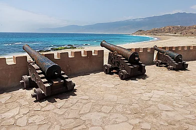 Shutterstock : Military cannons at Omans Mirbat Fort overlooking the sea