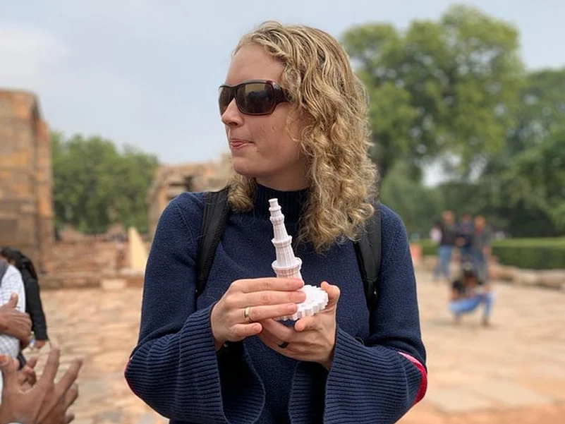 A blind traveller holds a 3D model of the Qutub Minar in Delhi.
