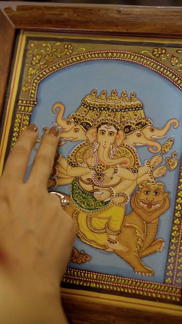 Copyright: Karnataka Tourism. All Rights Reserved : A woman feels the brushstrokes of a traditional Mysore painting