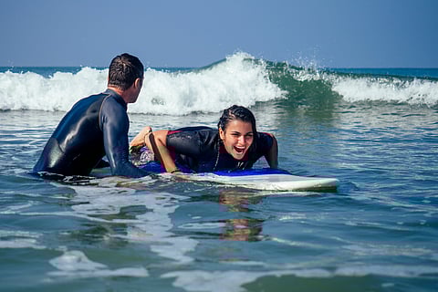 An instructor teaching a beginner how to paddle on a surfboard