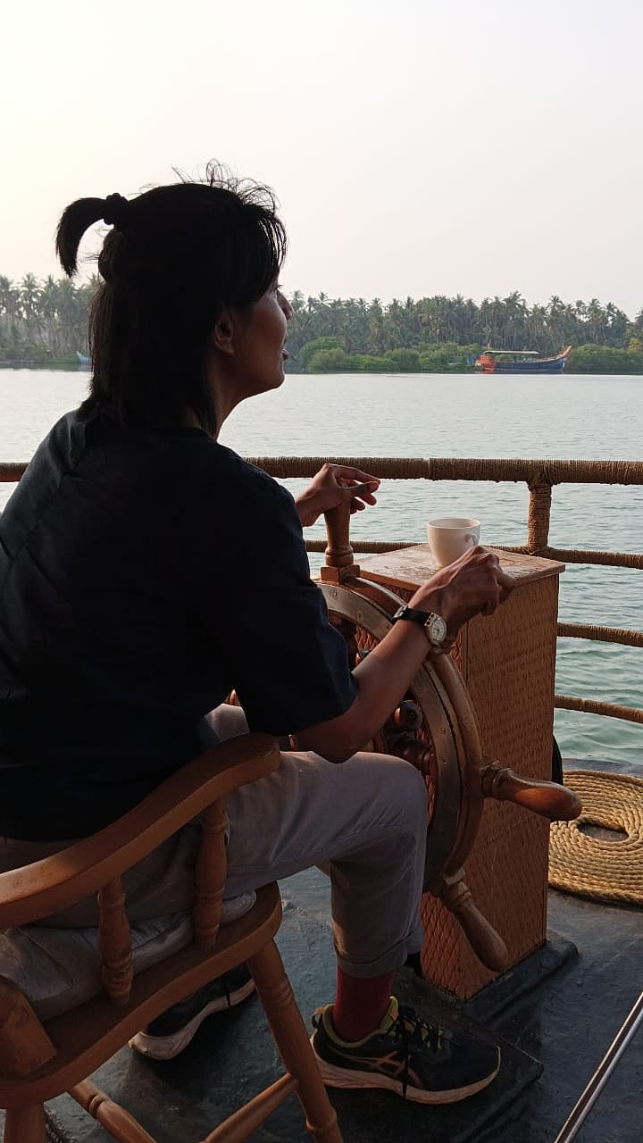 The writer steering the houseboat on the Tejaswini River