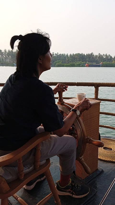 The writer steering the houseboat on the Tejaswini River