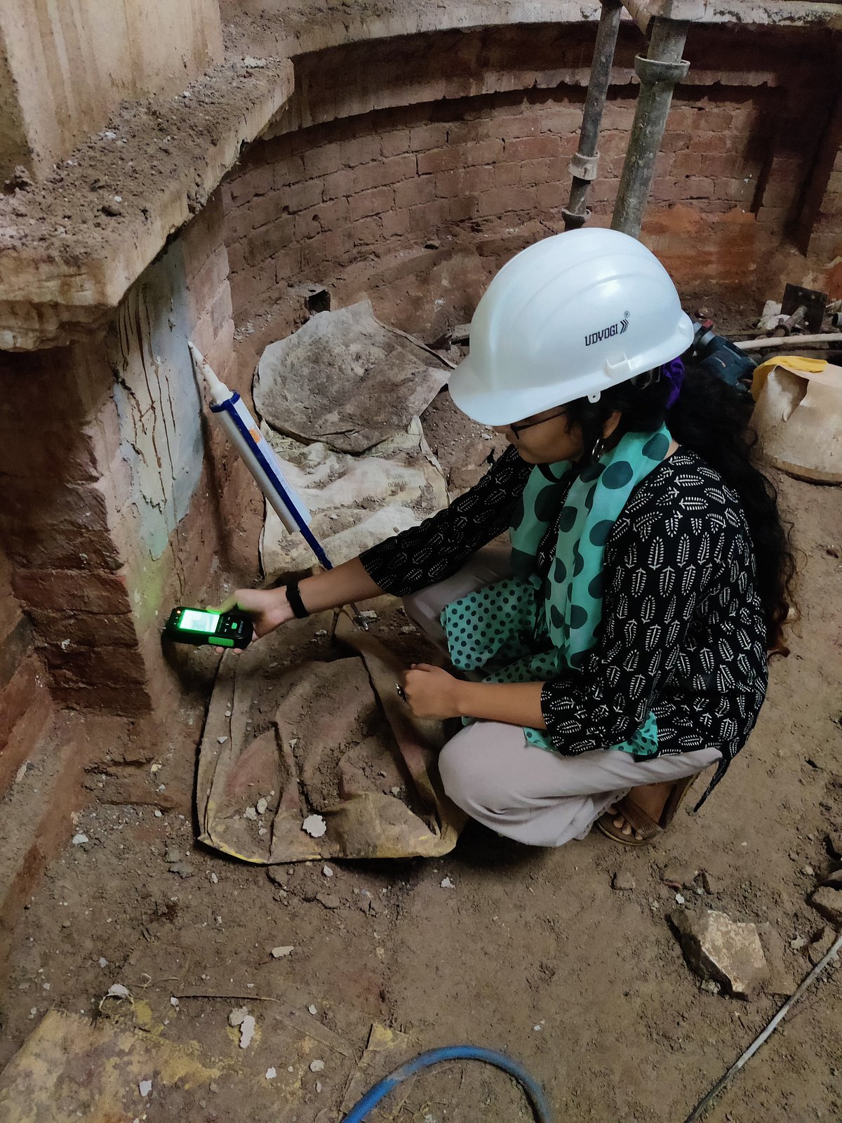 Khushi Shah tests the percentage of moisture in the brick masonry of a building