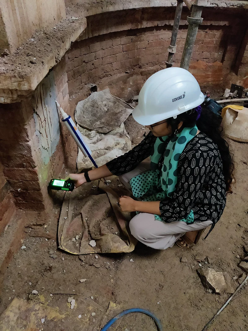 Khushi Shah tests the percentage of moisture in the brick masonry of a building