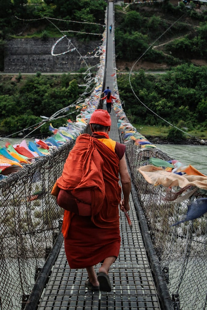 Shutterstock : A monk crosses a bridge at Punakha, Bhutan