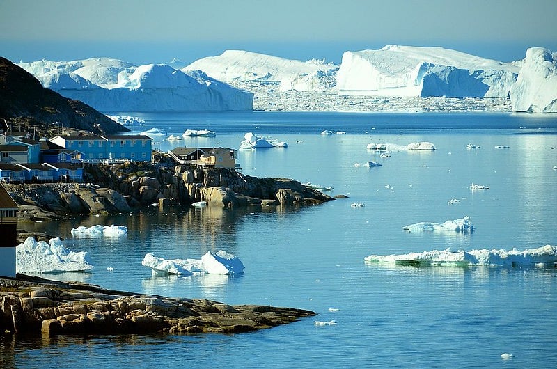 The breathtaking backdrop of the Ilulissat Icefjord, with its icebergs illuminated by the lights, enhances the spectacle
