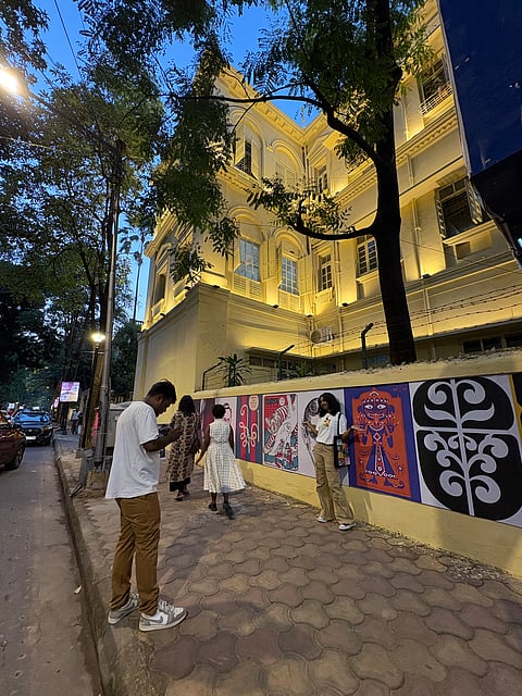 People posing against artworks by Satyajit Ray
