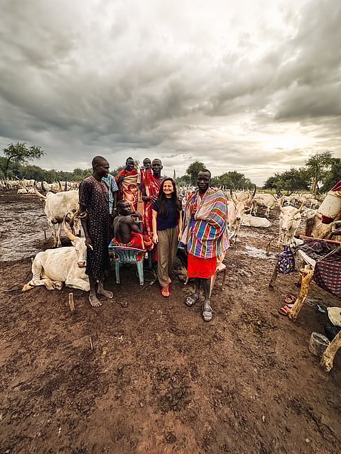 The author believes that travelling allows them to connect with people of different cultures (pictured here: author with the locals of South Sudan)