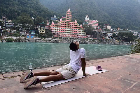 A man practices yoga next to the Ganges River in Rishikesh