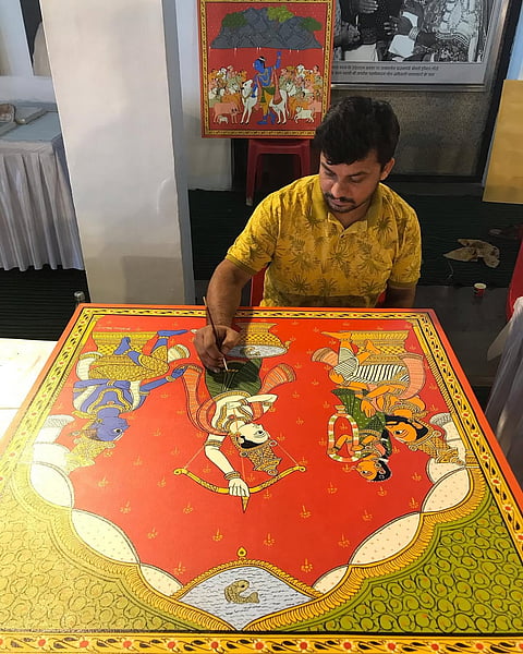 Vinay Kumar applying vibrant natural pigments to a Khadi canvas, tracing the signature profile outlines of Cheriyal lore
